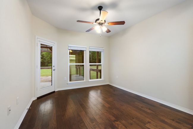 Empty room with dark wood-style flooring, baseboards, and a ceiling fan | Image 12