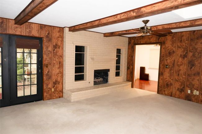 Unfurnished living room featuring wood walls, a ceiling fan, and carpet | Image 22