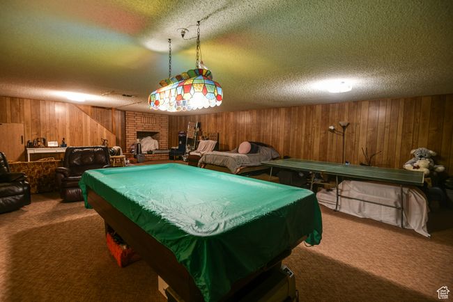 Playroom with wood walls, a textured ceiling, carpet, a brick fireplace, and pool table | Image 33