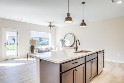 Kitchen featuring light wood-type flooring, dishwasher, sink, an island with sink, and decorative light fixtures | Image 2