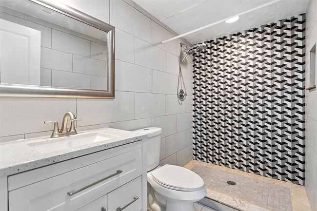 Bathroom featuring a stall shower, tile walls, vanity, and ceramic tile | Image 29