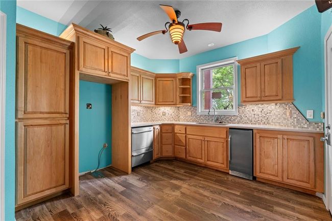 Kitchen featuring a sink, open shelves, backsplash, light countertops, and dishwasher | Image 50