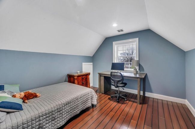 Bedroom featuring baseboards, lofted ceiling, visible vents, and wood finished floors | Image 15