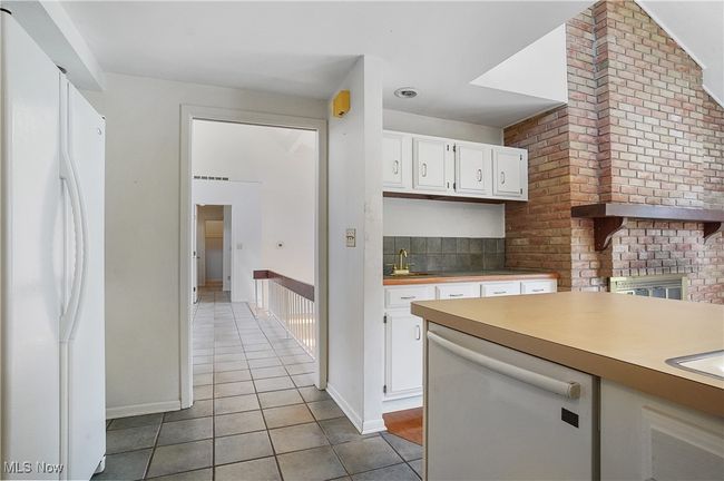 Kitchen with a sink, light tile patterned flooring, white appliances, light countertops, and white cabinetry | Image 14