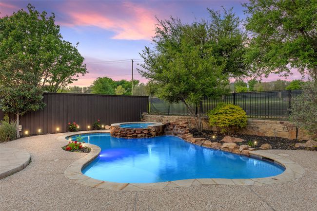 Pool at dusk featuring a pool with connected hot tub and a fenced backyard | Image 29