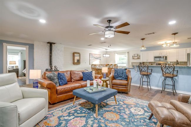 Living area featuring visible vents, ceiling fan, wood finished floors, and a wood stove | Image 24