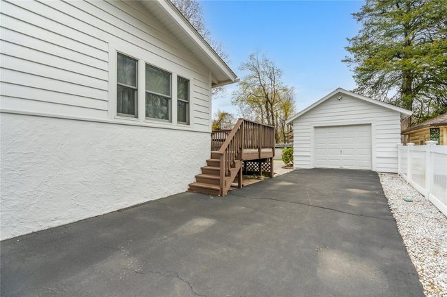 View of side of property featuring stairs, fence, a wooden deck, an outdoor structure, and a detached garage | Image 32