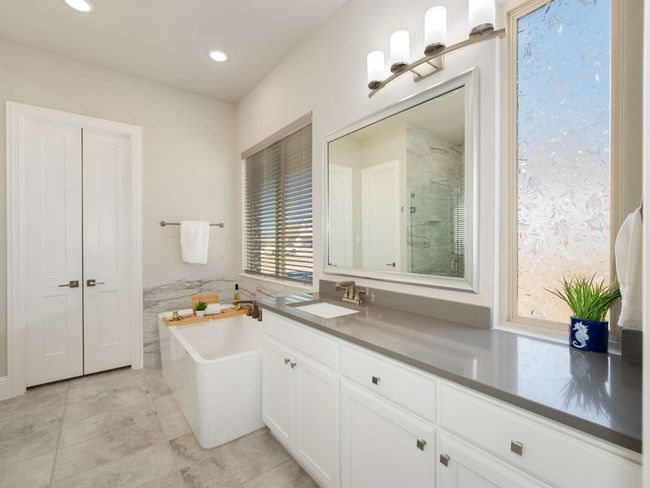 Primary spa-like bathroom with dual quartz-topped vanities, a freestanding soaking tub, and an oversized frameless shower with bench | Image 15