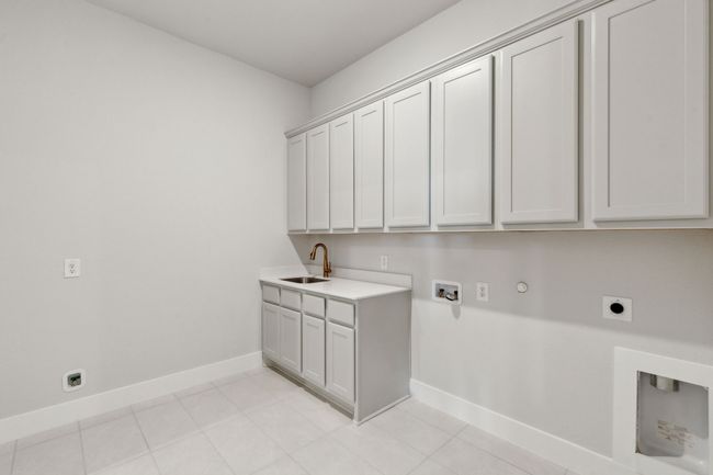 Laundry room with hookup for an electric dryer, cabinet space, gas dryer hookup, hookup for a washing machine, and light tile patterned flooring | Image 5