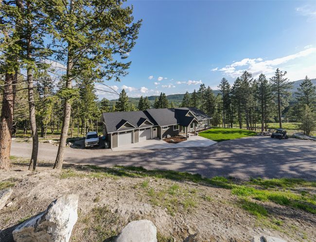 View of front of home with a mountain view, dirt driveway, an attached garage, and roof with shingles | Image 57