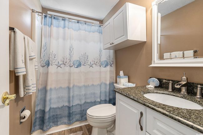 Bathroom with toilet, vanity, a shower with curtain, and wood finished floors | Image 28