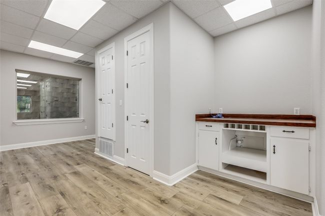 Hallway featuring a paneled ceiling, visible vents, baseboards, and light wood-type flooring | Image 21