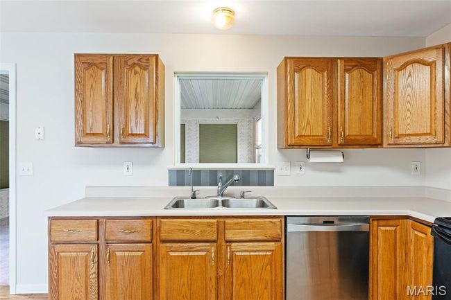 Kitchen featuring stainless steel dishwasher, a sink, light countertops, and brown cabinets | Image 9