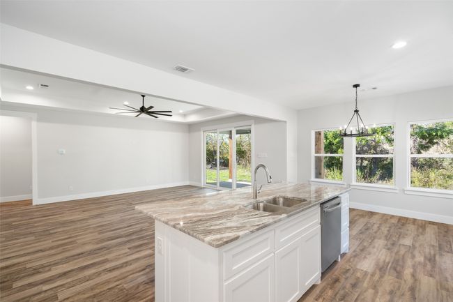 Kitchen with dishwasher, a kitchen island with sink, sink, light stone counters, and white cabinetry | Image 15