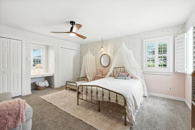 Bedroom with two closets, wallpapered walls, carpet floors, and ceiling fan | Image 23