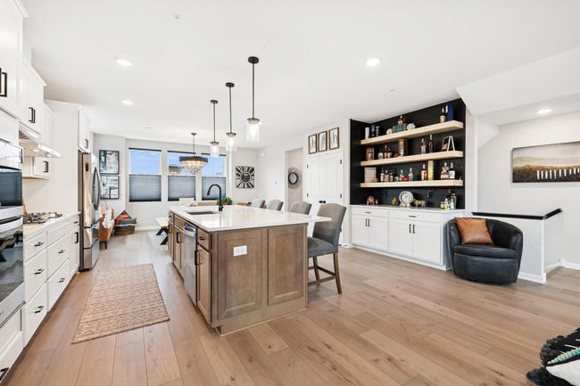 Bright and open, this stunning kitchen and dining area features a spacious center island, designer lighting, and a custom built-in bar—perfectly blending function and style for everyday living and effortless entertaining. | Image 9