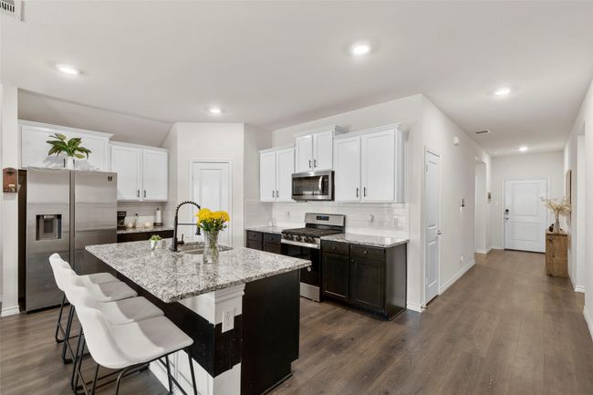 Kitchen featuring decorative backsplash, stainless steel appliances, a sink, and dark wood-style flooring | Image 12