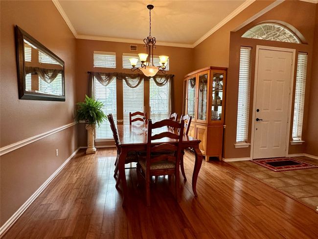 Dining area with ornamental molding, hardwood / wood-style flooring, baseboards, and a chandelier | Image 11
