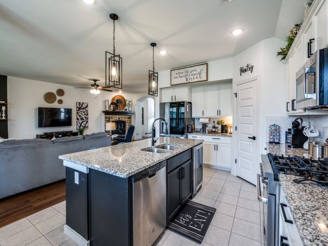 Kitchen with stainless steel appliances, a sink, white cabinetry, a fireplace, and light tile patterned floors | Image 16
