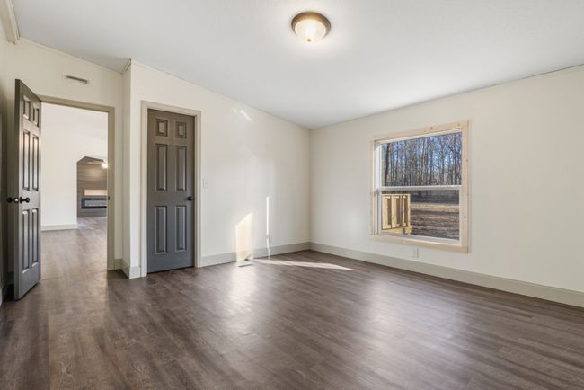The primary bedroom offers a peaceful retreat with a serene view of the wooded front yard and the convenience of a private en-suite bathroom, creating a comfortable and relaxing space to unwind. | Image 13