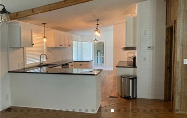 Kitchen featuring a peninsula, pendant lighting, a sink, and dark countertops | Image 16