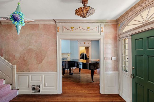 Entrance foyer featuring a decorative wall, wood finished floors, wainscoting, and stairway | Image 9