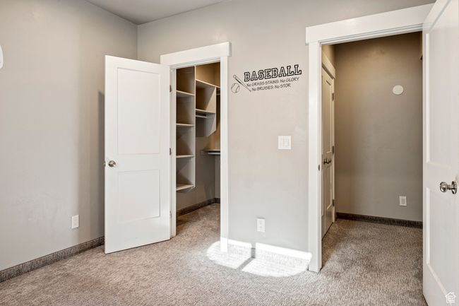 Unfurnished bedroom with a closet, a spacious closet, carpet flooring, and baseboards | Image 30