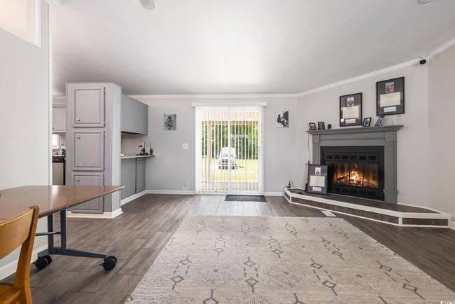 Unfurnished living room with crown molding, dark wood finished floors, and a glass covered fireplace | Image 8