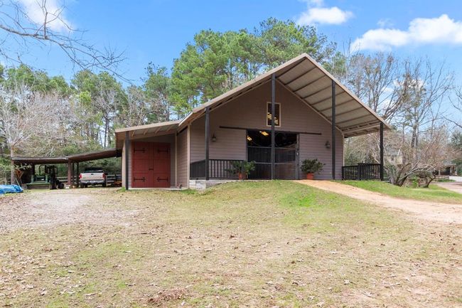 An impressive crushed granite driveway leads down to the barn. A grand entrance marked by the towering covered patio extending 36' wide and 12' deep commands attention. Just like the residence, this barn was built to withstand up to 190mph winds. It is powered by its own 200 amp electrical box providing electricity and light to the interiors. Multiple skylights help keep the horses on their natural sleep schedules and provide additional natural light. | Image 41