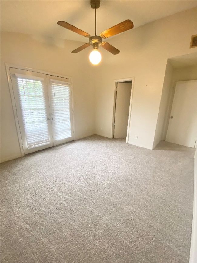 Empty room featuring light colored carpet, visible vents, french doors, and a ceiling fan | Image 7