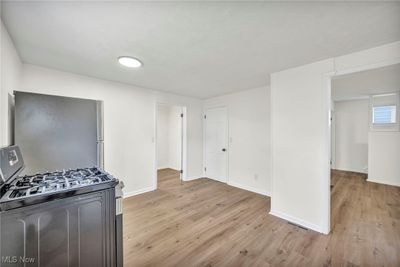 Kitchen with light wood-type flooring, gas range, and stainless steel fridge | Image 3