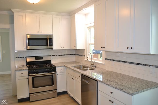 New kitchen featuring decorative backsplash, white cabinets, and appliances with stainless steel finishes | Image 16
