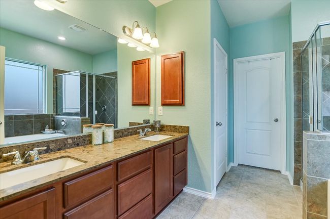 Bathroom featuring a shower stall, double vanity, baseboards, tile patterned floors, and a bathtub | Image 16