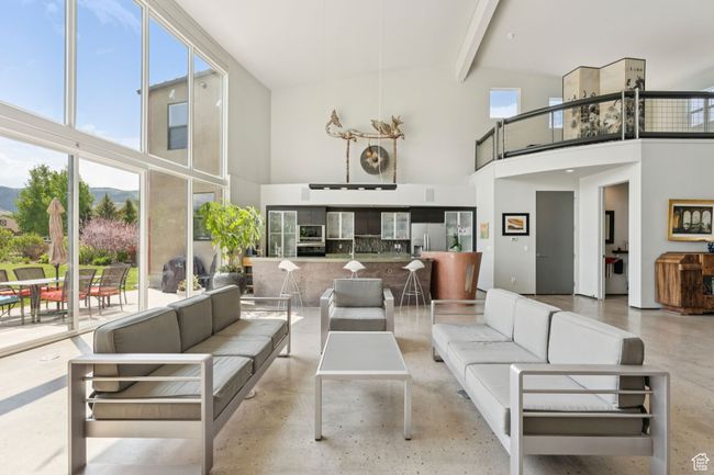 Living room with a towering ceiling, concrete floors, and beamed ceiling | Image 4