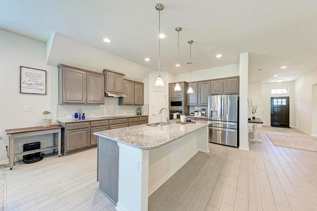 Another view of the kitchen reveals the corner pantry closet, all cabinetry, abundant countertop space and the foyer. | Image 14