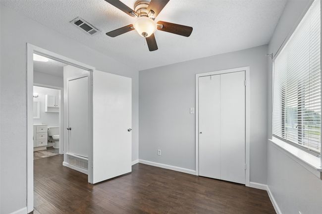 Unfurnished bedroom featuring dark wood finished floors, a closet, a textured ceiling, ceiling fan, and connected bathroom | Image 14