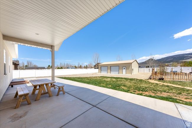 View of patio featuring a detached garage, a fenced backyard, an outdoor structure, and outdoor dining space | Image 54