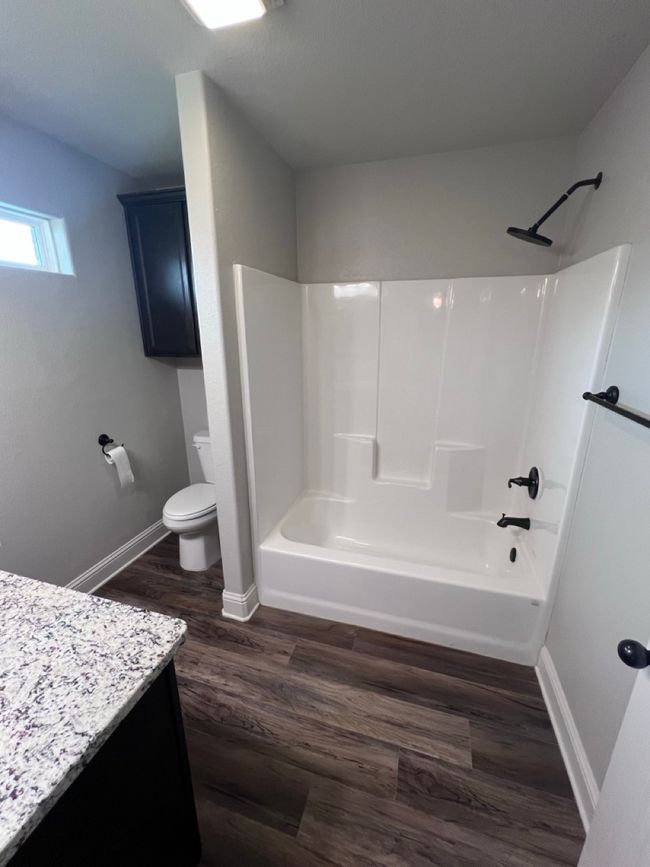 Bathroom with vanity, toilet, wood finished floors, shower / tub combination, and baseboards | Image 39