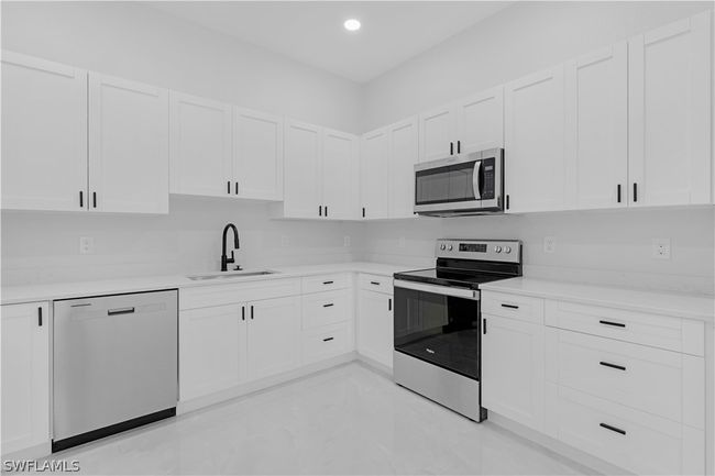 Kitchen featuring white cabinetry, appliances with stainless steel finishes, sink, and light tile flooring | Image 32