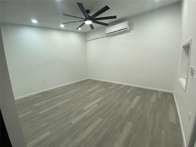 Unfurnished room featuring an AC wall unit, baseboards, wood finished floors, and recessed lighting | Image 7
