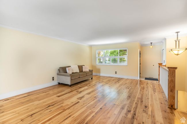 Interior space with light wood finished floors, visible vents, ornamental molding, an upstairs landing, and baseboards | Image 6