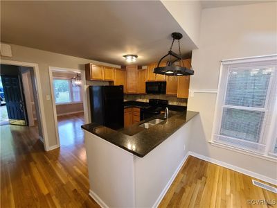 Kitchen with dark wood-type flooring, kitchen peninsula, pendant lighting, black appliances, and sink | Image 2