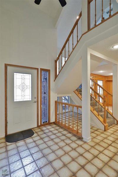 Tiled foyer entrance with a healthy amount of sunlight, a high ceiling, and ceiling fan | Image 2