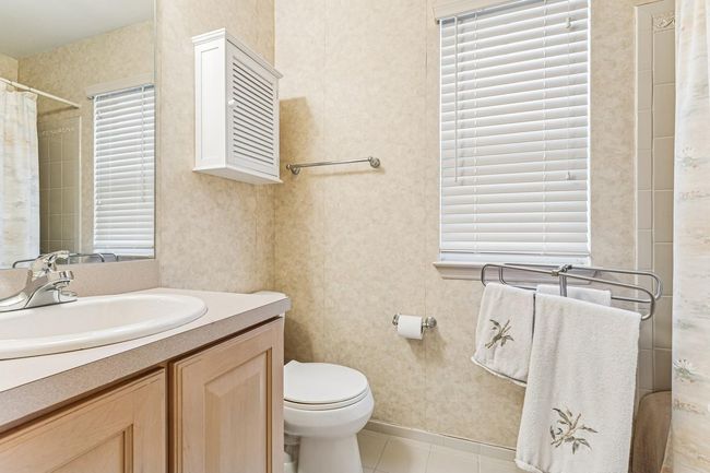 Full bathroom with toilet, wallpapered walls, vanity, a shower with curtain, and tile patterned flooring | Image 21