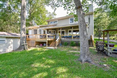 This back view of the home highlights the large, extended patio, perfect for outdoor gatherings and relaxation. The photo also shows the easy access to a convenient half bath with a private entrance, ideal for guests enjoying the outdoor space. | Image 3