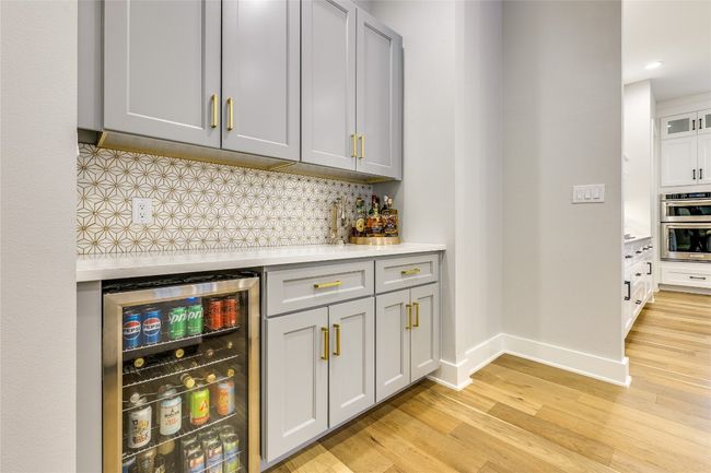 Indoor bar or buffet with wine cooler, gold glittered backsplash, and quartz countertops. | Image 18