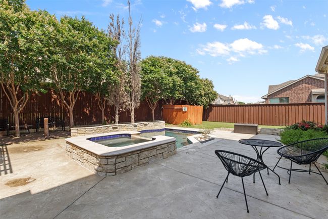 Fenced backyard with a patio area and a pool with connected hot tub | Image 39