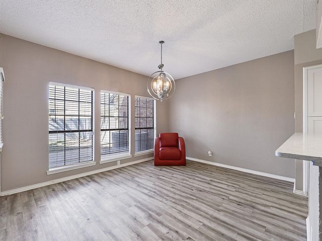 Unfurnished room with a textured ceiling, wood finished floors, baseboards, and a chandelier | Image 7
