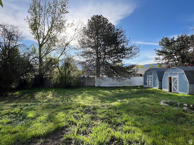 View of yard with fence, an outdoor structure, and a shed | Image 9