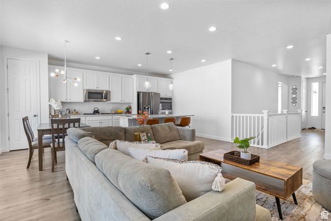 Living area with a notable chandelier, baseboards, light wood-style flooring, and recessed lighting | Image 23